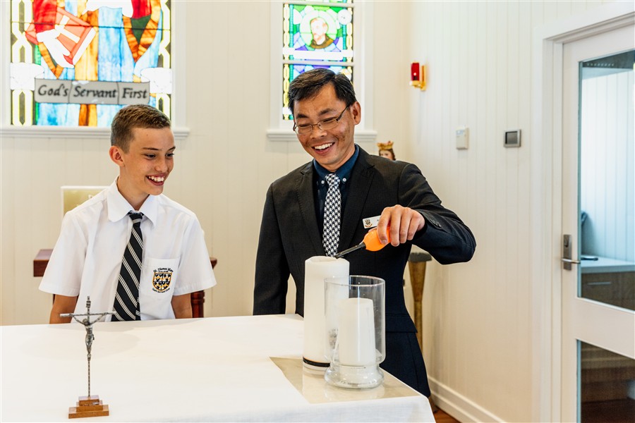 Male teacher and student lighting candle in our Chapel