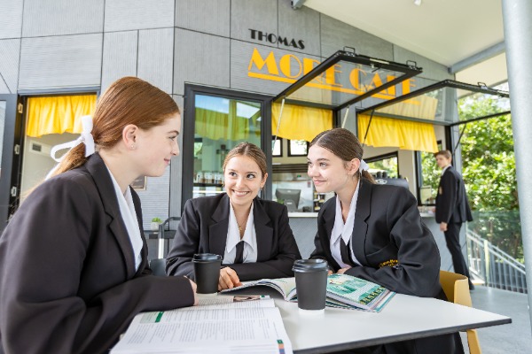 students studying together at a table near the campus café, highlighting collaboration, peer support and a connected learning environment