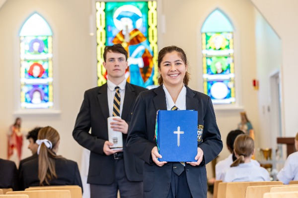 Female and Male student walking down altar in chapel with bible and candle.jpg