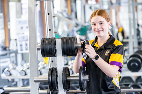 female student placing weights on gym machinery