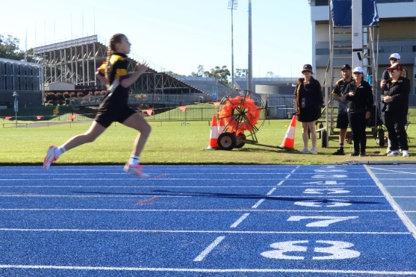 girl student running through finish line of athletics track.jpg