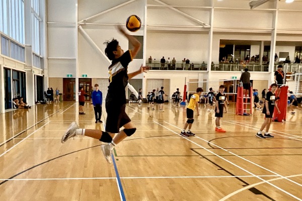 male student off ground hitting volleyball over nets.jpg