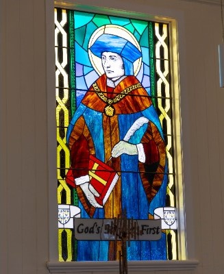 stained glass window of Saint Thomas More holding a book, representing faith, learning and spiritual formation