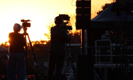 camera operators working with filming equipment during an outdoor production, reflecting hands on media training, collaboration and industry experience