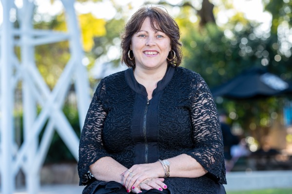 staff member seated outdoors on campus, representing leadership, approachability and a supportive school community