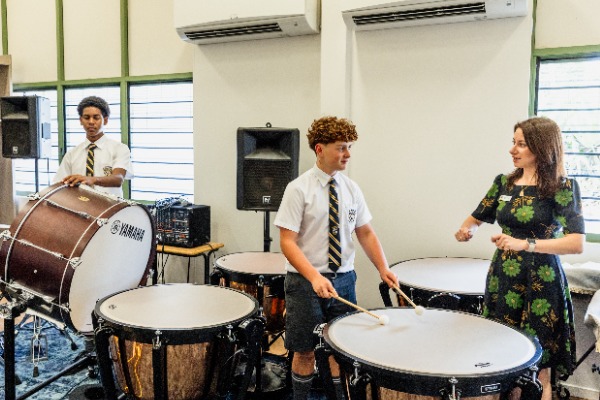 students and teacher engaged in a percussion lesson using drums, reflecting music education, collaboration and skill development