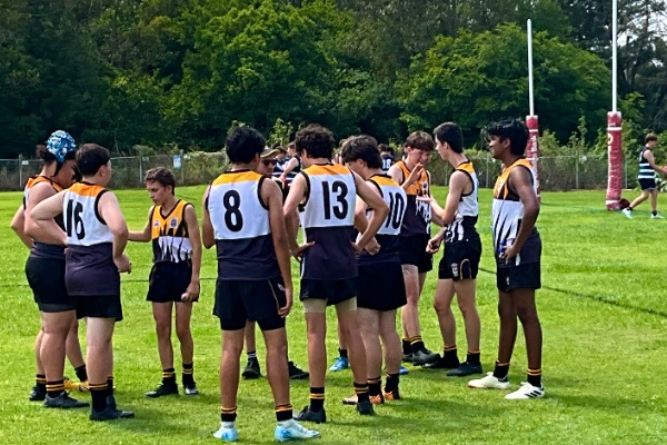 school sports team gathered in a field huddle listening to a coach, reflecting teamwork, strategy and collaboration