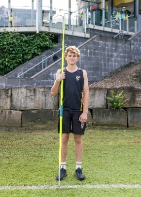 student standing on a sports field holding a javelin, representing athletics training, skill development and participation in school sport