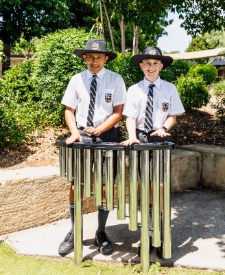 students playing outdoor percussion chimes in a garden setting, reflecting creative expression, engagement and learning beyond the classroom