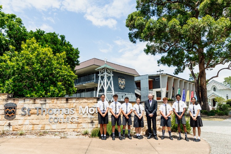 students and principal standing together at the college entrance, representing leadership, community and school identity