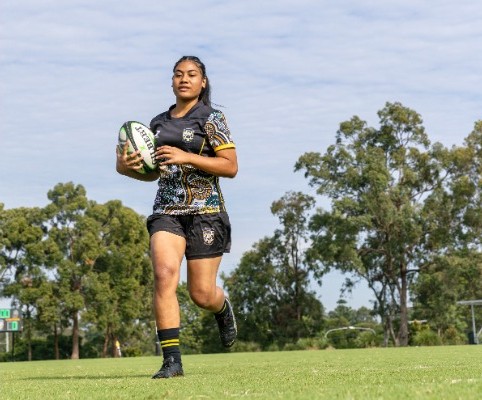 student running with a rugby ball across a sports field, representing speed, strength and active participation in school sport