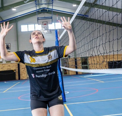 student positioned at the net preparing to set the ball, reflecting teamwork, coordination and game awareness