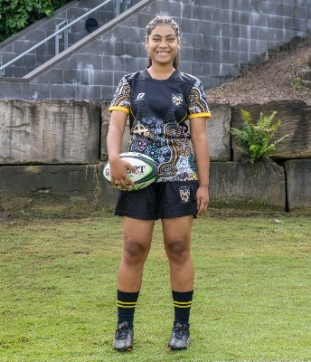 student standing with a rugby ball on a field in uniform, representing confidence, readiness and school sport identity