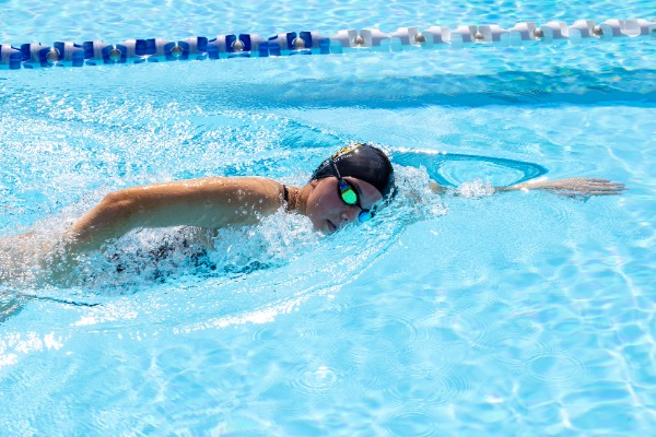 student swimming freestyle in a lane at the pool, highlighting endurance, skill and active participation