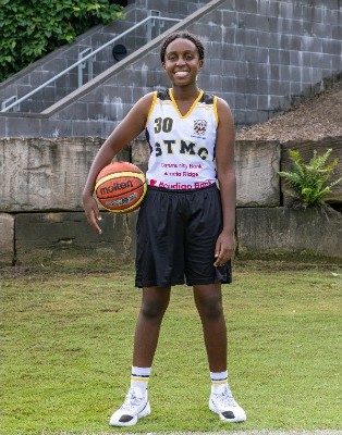 student standing with a basketball on a sports field in uniform, representing confidence, participation and school sport identity