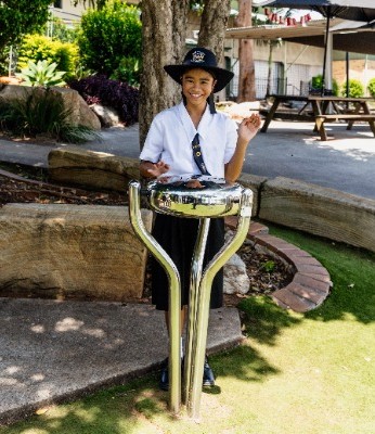 student playing a single outdoor percussion instrument on school grounds, representing creativity, confidence and participation in music
