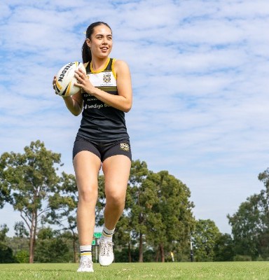 student holding a rugby ball while scanning the field, representing awareness, teamwork and game strategy