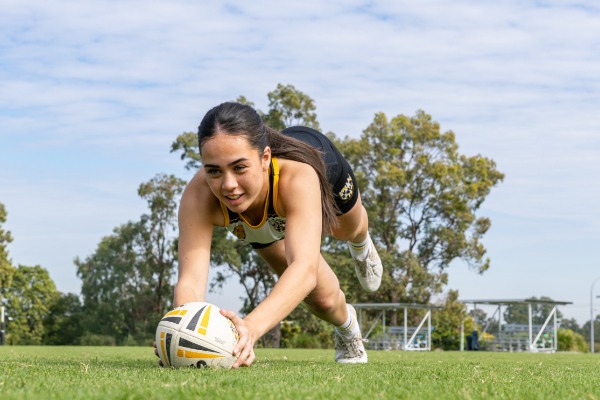 student diving forward to ground a rugby ball on the field, highlighting effort, determination and active participation in school sport