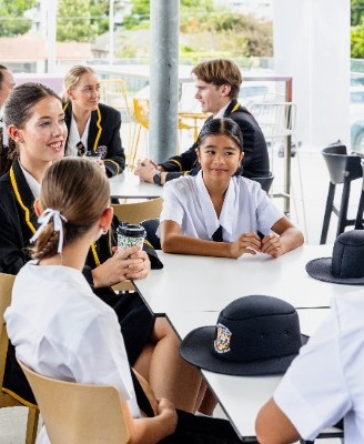 students gathered around a table in discussion, reflecting connection, student voice and collaborative learning