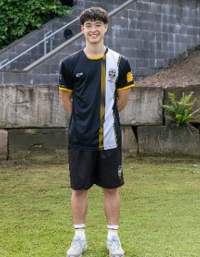 student standing in athlete uniform on school grounds, representing team identity, readiness and participation in sport