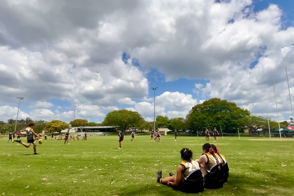 students participating in an outdoor field game with peers watching from the sidelines, reflecting active participation, teamwork and school sport