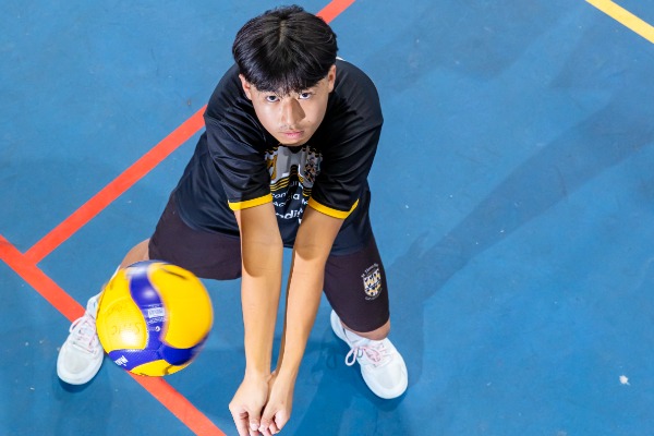 student performing a forearm pass to control the volleyball during play, highlighting skill development and teamwork