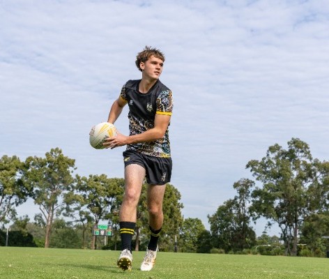 student preparing to pass a rugby ball while moving across the field, highlighting coordination, decision making and teamwork