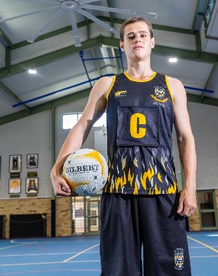 student in netball uniform holding a ball on an indoor court, reflecting confidence, skill and involvement in school sport
