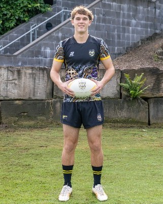 student standing with a rugby ball on a field in uniform, representing confidence, readiness and school sport identity