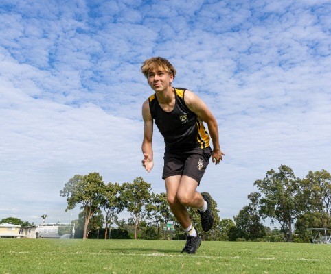 student sprinting forward on a sports field, representing speed, fitness and participation in athletics