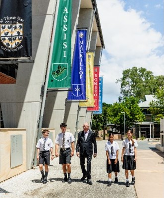 principal walking with students along campus featuring college house banners, representing guidance, belonging and school tradition