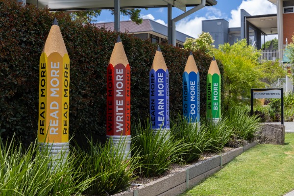 colourful pencil sculptures displayed along a garden path with messages promoting reading, writing, learning and growth, highlighting school values and a culture of learning