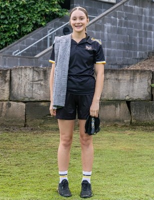 student standing in swim uniform holding towel and gear, representing team identity and readiness for competition