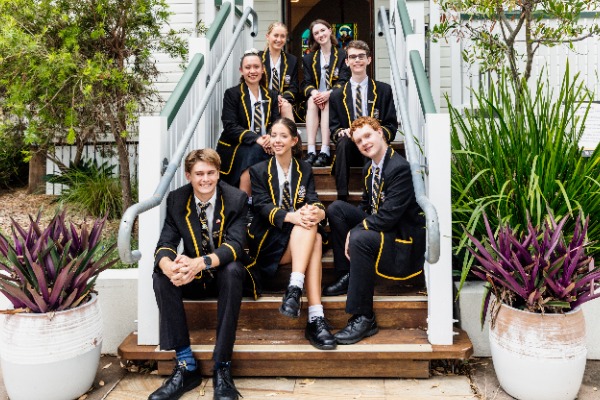 group of students seated together on steps outside a school building, representing friendship, belonging and student life