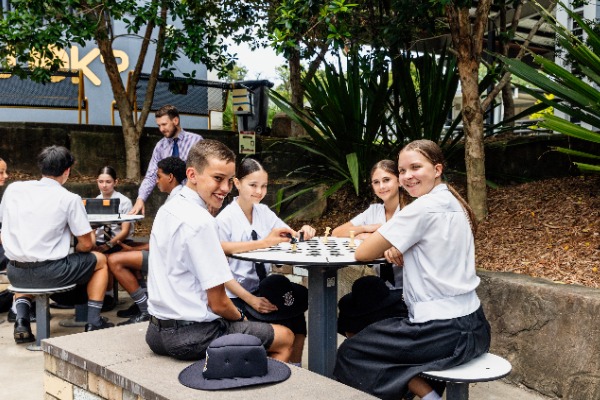 students gathered outdoors in a break area playing a board game, reflecting social connection, wellbeing and a positive school community