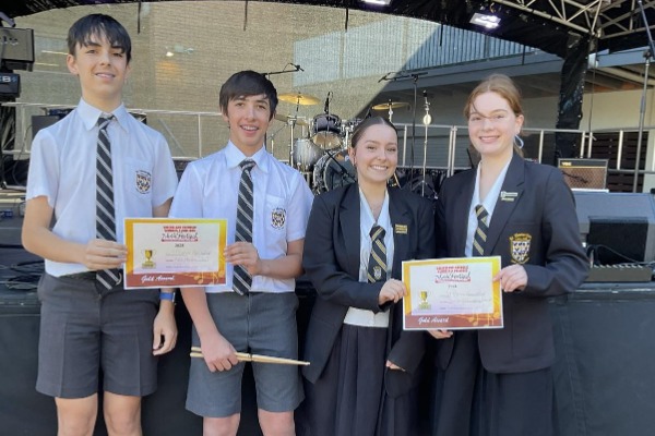 students holding award certificates on a stage, highlighting achievement, recognition and student success