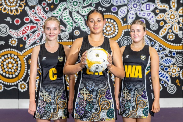 students in netball uniform standing together with a ball in front of a patterned backdrop, representing teamwork, identity and participation in school sport
